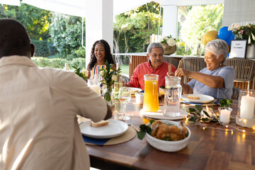 Family enjoying outdoor meal together, sharing laughter and conversation at table