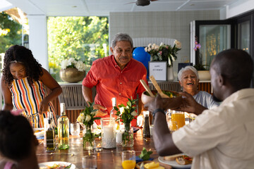 Family enjoying outdoor meal together, sharing laughter and conversation at table