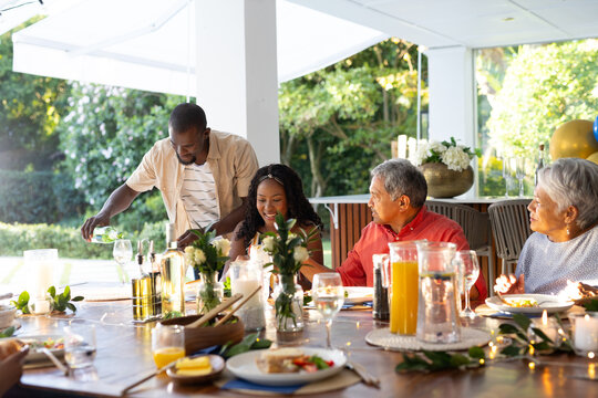 African American family sharing laughter and conversation during outdoor meal together