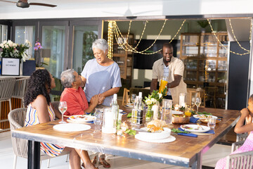 Family sharing festive meal, laughing and talking around dining table at home