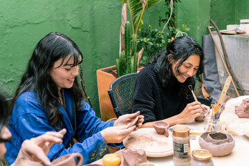 Two South American women happily shaping pottery in a vibrant workshop, enjoying their craft and celebrating creativity together