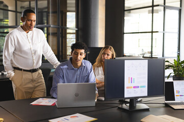 Business team collaborating on laptop and reviewing data charts in modern office