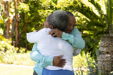 Senior couple embracing warmly in lush garden, enjoying sunny day together