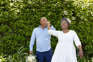 Senior couple dancing joyfully in garden, holding hands and smiling brightly © WavebreakMediaMicro