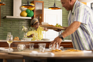 Preparing meal in modern kitchen, senior couple sharing wine and conversation