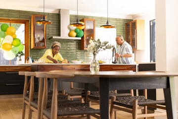 In modern kitchen, senior couple preparing meal, sharing each other's company