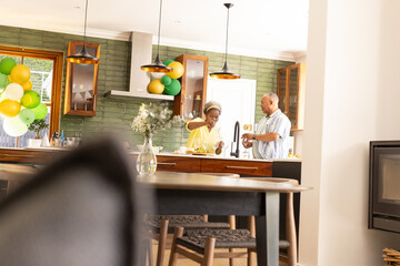 In kitchen, African American senior couple preparing meal, smiling warmly together