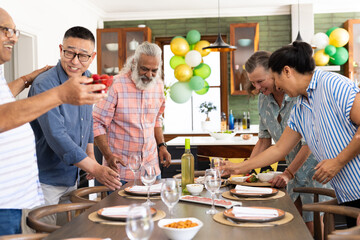 Group of seniors joyfully setting dining table for festive gathering at home