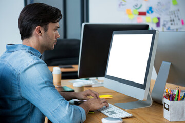 Typing man working on computer at wooden desk in modern office, with coffee cup, copy space