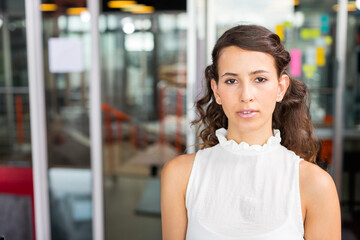 Standing woman posing by glass partitions in office, colorful sticky notes, copy space