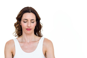 Fototapeta premium Meditating woman standing with eyes closed in studio with plain white background, serene expression