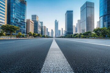 Wide empty city street lined with tall glass and concrete skyscrapers under clear blue sky conveying calm urban atmosphere