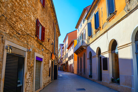 Fototapeta Charming narrow street in Pula, Croatia, lined with old stone and colorful buildings featuring arched windows. Sunny weather highlights vibrant architecture and creates inviting atmosphere in old town