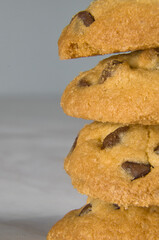 Four stacked chocolate chip cookies, on a gray background with space for text