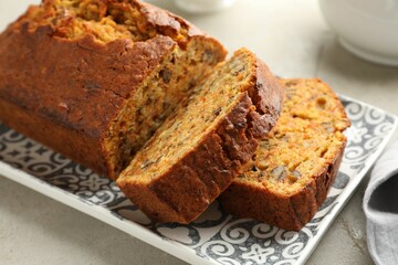 Cut homemade carrot cake with nuts on light grey table, closeup