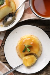 Delicious pudding with caramel sauce and mint served on wooden table, flat lay