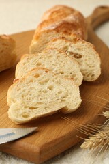 Slices of fresh bread and spikelets on light textured table, closeup