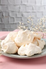 Delicious homemade meringue cookies on pink table, closeup