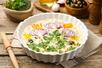 Raw focaccia with vegetables, olives, spices and brush on wooden table, closeup