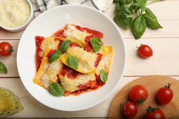Delicious ravioli with tomato sauce, parmesan cheese and basil on white wooden table, flat lay