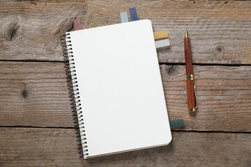 Pen, open notebook and colorful stickers on wooden table, flat lay
