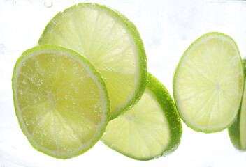 Refreshing soda water with slices of lime in glass on white background, closeup