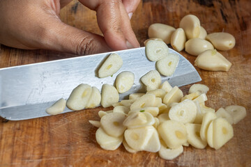 Slicing garlic on a kitchen cutting board, close up
