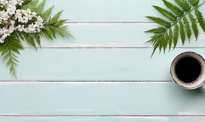 Aesthetic Flat Lay with Fresh Green Leaves, White Flowers, and a Cup of Black Coffee on Powder Blue Wooden Background for Inviting Atmosphere