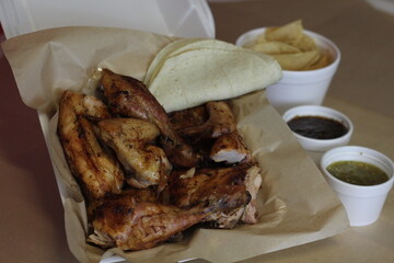 This appealing image features a takeaway box filled with succulent grilled chicken pieces served...