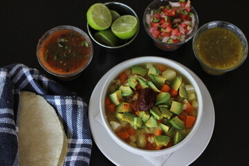 A vibrant bowl of vegetable tlalpeño soup featuring fresh avocado, carrots, and delicious toppings, ideal for a healthy meal with refreshing lime on the side, ready to enjoy.