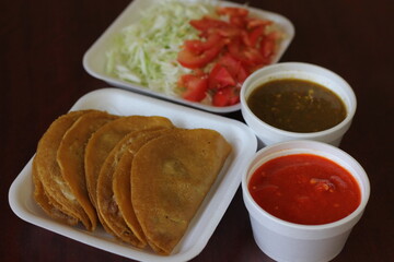 This image shows a plate of traditional, crispy tacos served with fresh salsa and sauces, embodying the spirit of authentic Mexican cuisine and cultural joy.