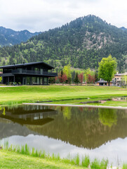 Black and White House on Grassy Hills with Reflecting Lake and Colorful Trees