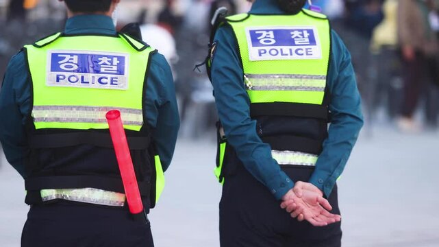 Korean police squad formation in uniform with "Police" logo, policemen officer patrol maintain public order during political demonstration protest rally in the streets of Busan center, South Korea 