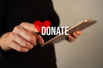 Woman holding a tablet while pointing at a heart icon with the word donate