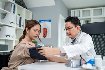 Fototapeta premium Asian doctor examine patient woman use blood pressure gauge in hospital. 