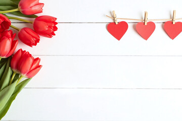 three red hearts hanging on a clothes line next to a vase of tulips