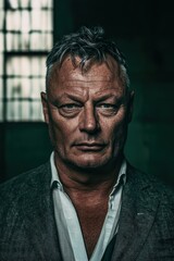 Obraz premium Intense portrait of a mature man with a stern gaze, wearing a suit and open-collared shirt, dramatically lit with green tones