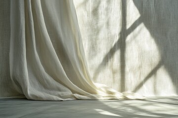 Beige linen curtain cascading with sunlight casting shadows on textured backdrop studio shot