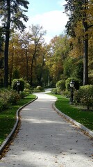 Fototapeta premium Winding path through autumnal park, sunlight filtering through trees Well-maintained landscaping, manicured lawns, and decorative lighting