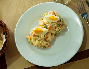 Portion of Olivier salad, typical Soviet cuisine appetizer of potatoes, carrots, pickled cucumbers, eggs and green peas, dressed with mayonnaise