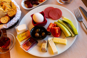 Halal breakfast including several kinds of cheese, sausage slices, eggs, fresh vegetables, olives and bread traditionally served with tea in Turkish hotel.