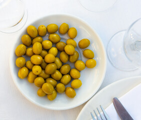 Plate with delicious pickled whole olives on dining table. Popular Spanish snack.
