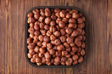 forest nuts peeled in square plate on wooden table background. vegetarian organic food for healthy diet.