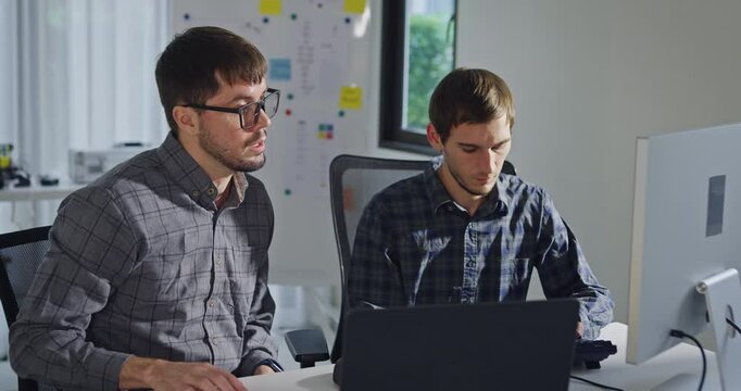 Team adult male engineer collaborate on robotic hand project using AI code solutions machine learning at tech workspace. Artificial intelligence interface, collaboration support prototype development.