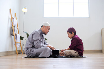 Fototapeta premium Portrait Of Indonesian Muslim Father Teaching His Son To Read The Quran