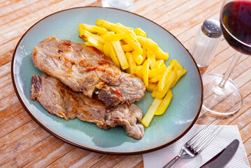 Delicious homemade roasted pork meat on bone served with fried potato ..