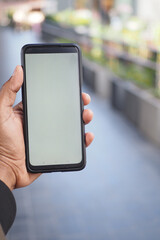 Hand holding smartphone on a city street during the day