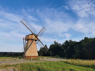 Fototapeta premium Windmill stands tall against a blue sky in a tranquil landscape showcasing nature and history at a rural location during daylight