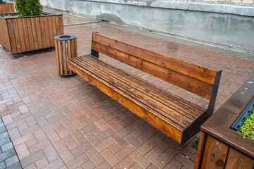 A wet wooden bench near the facade of an old house in the rain.
