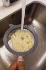 Washing rice in a kitchen sink before cooking for a meal preparation